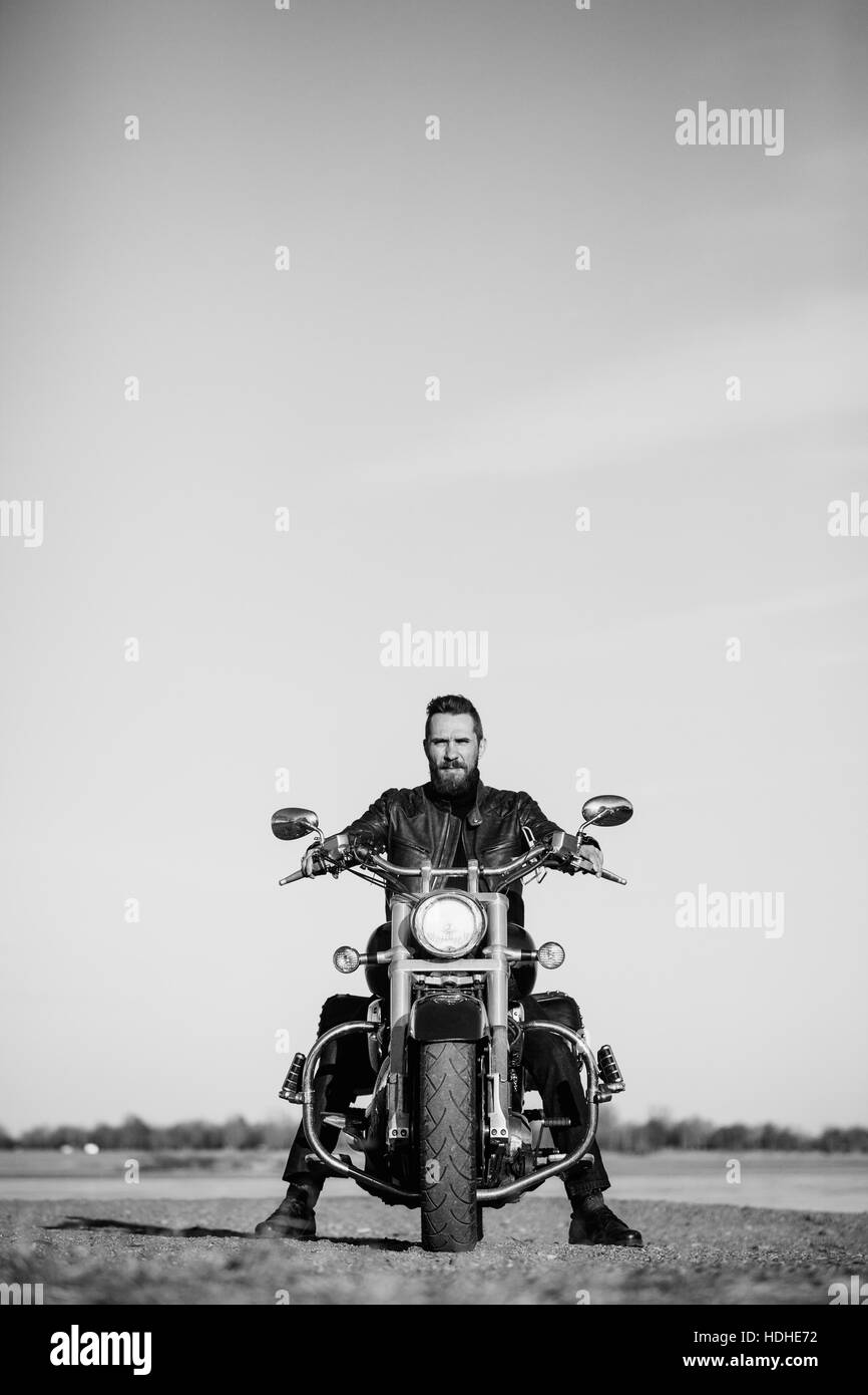A piena lunghezza Ritratto di biker seduto sul motociclo contro il cielo chiaro Foto Stock