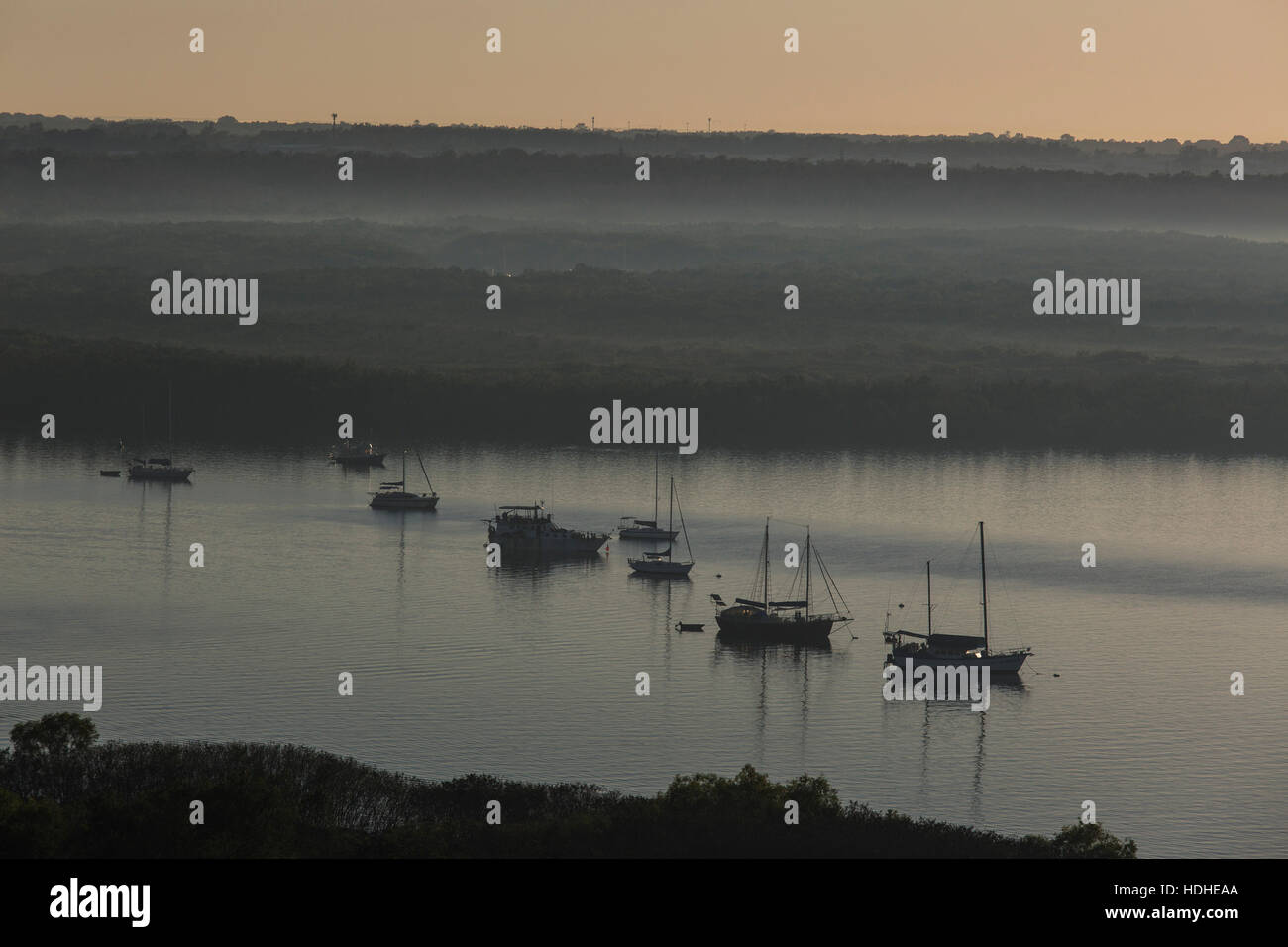 Angolo di alta vista delle barche a vela sul fiume nella nebbia meteo durante il tramonto Foto Stock