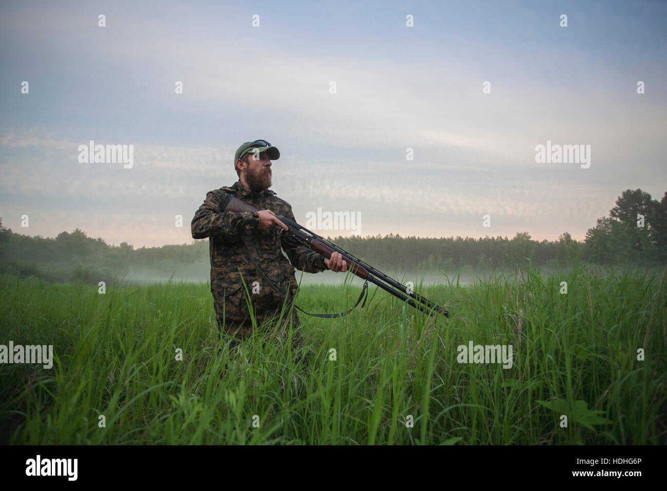 Hunter fucile di contenimento mentre si sta in piedi sul campo contro sky Foto Stock