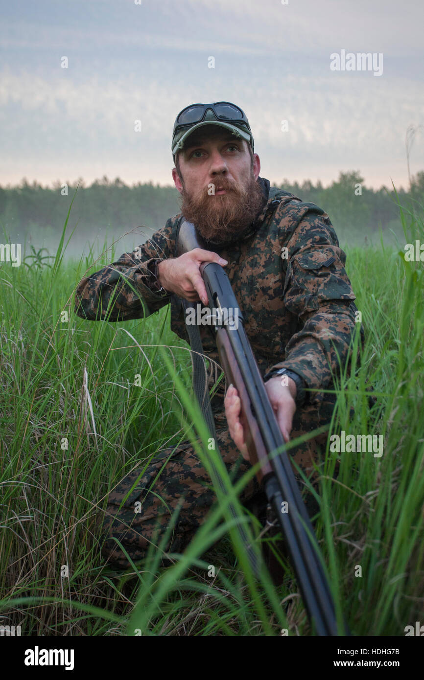 Hunter fucile di contenimento mentre cerchi di distanza sul campo Foto Stock