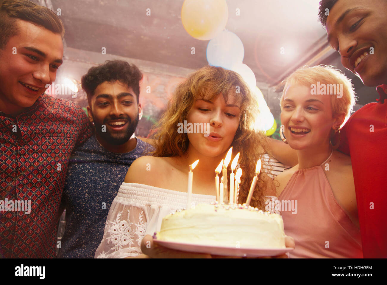 Donna candele di soffiaggio mentre festeggia il compleanno con gli amici in cantiere Foto Stock