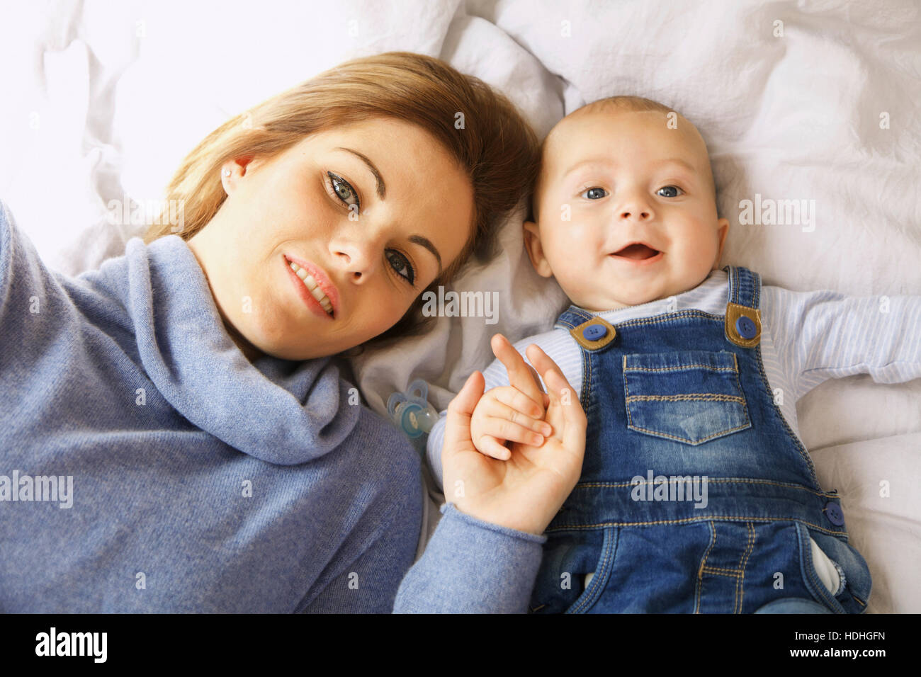 Direttamente sopra il colpo di felice madre giacente con simpatici baby boy sul letto Foto Stock