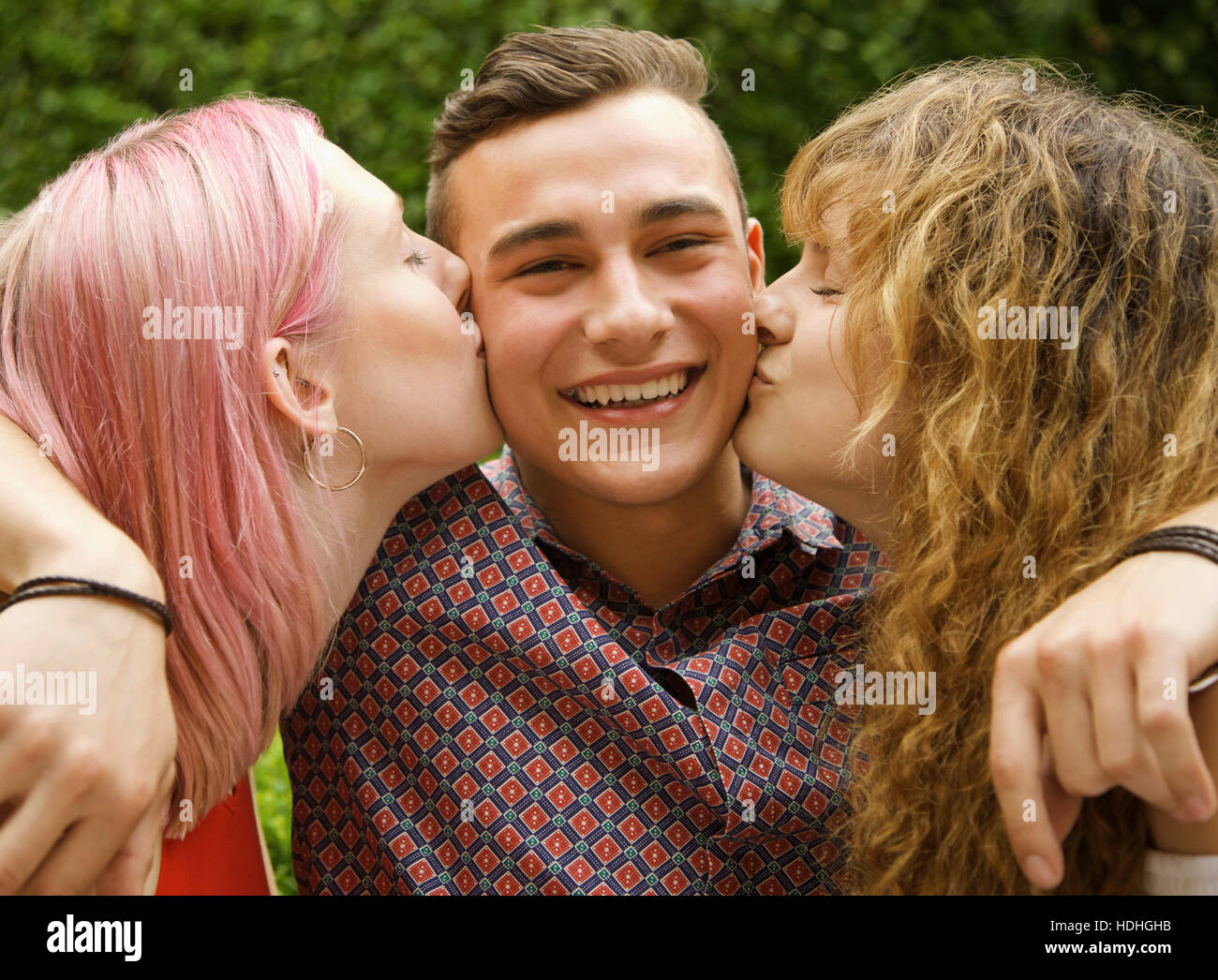 Vista laterale di donne baciare uomo sulle guance in cantiere Foto Stock