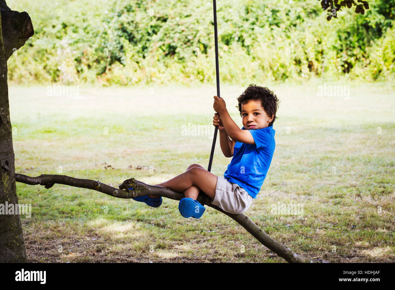 Ritratto di giovane ragazzo seduto su un albero di rotazione. Foto Stock