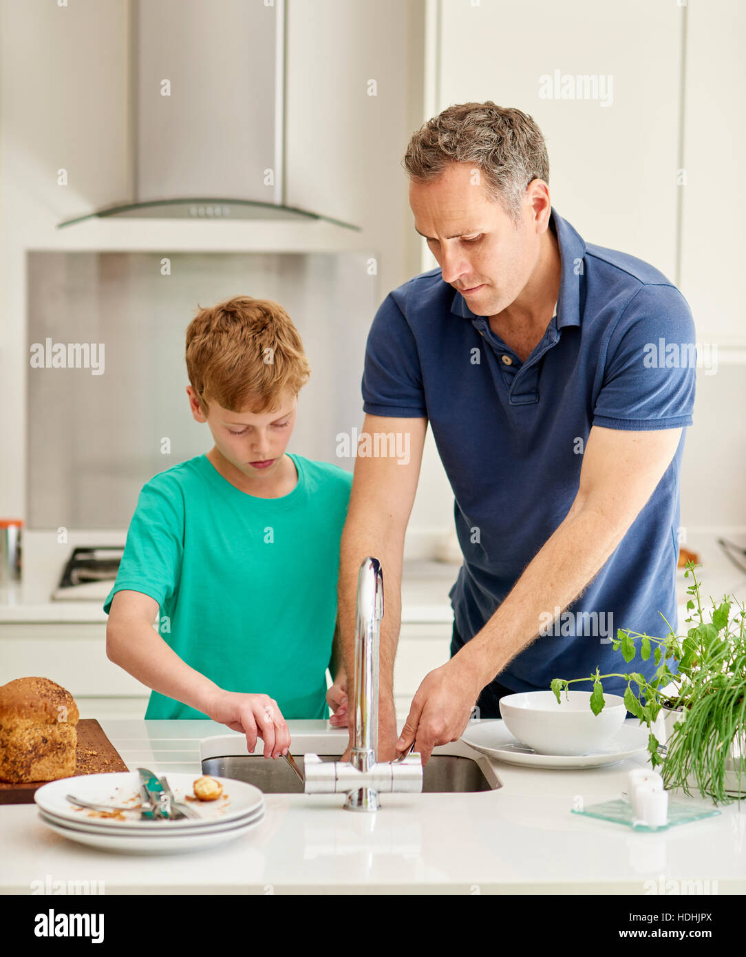 La casa di famiglia. Un uomo e un ragazzo in cucina affiancati facendo i piatti. Foto Stock