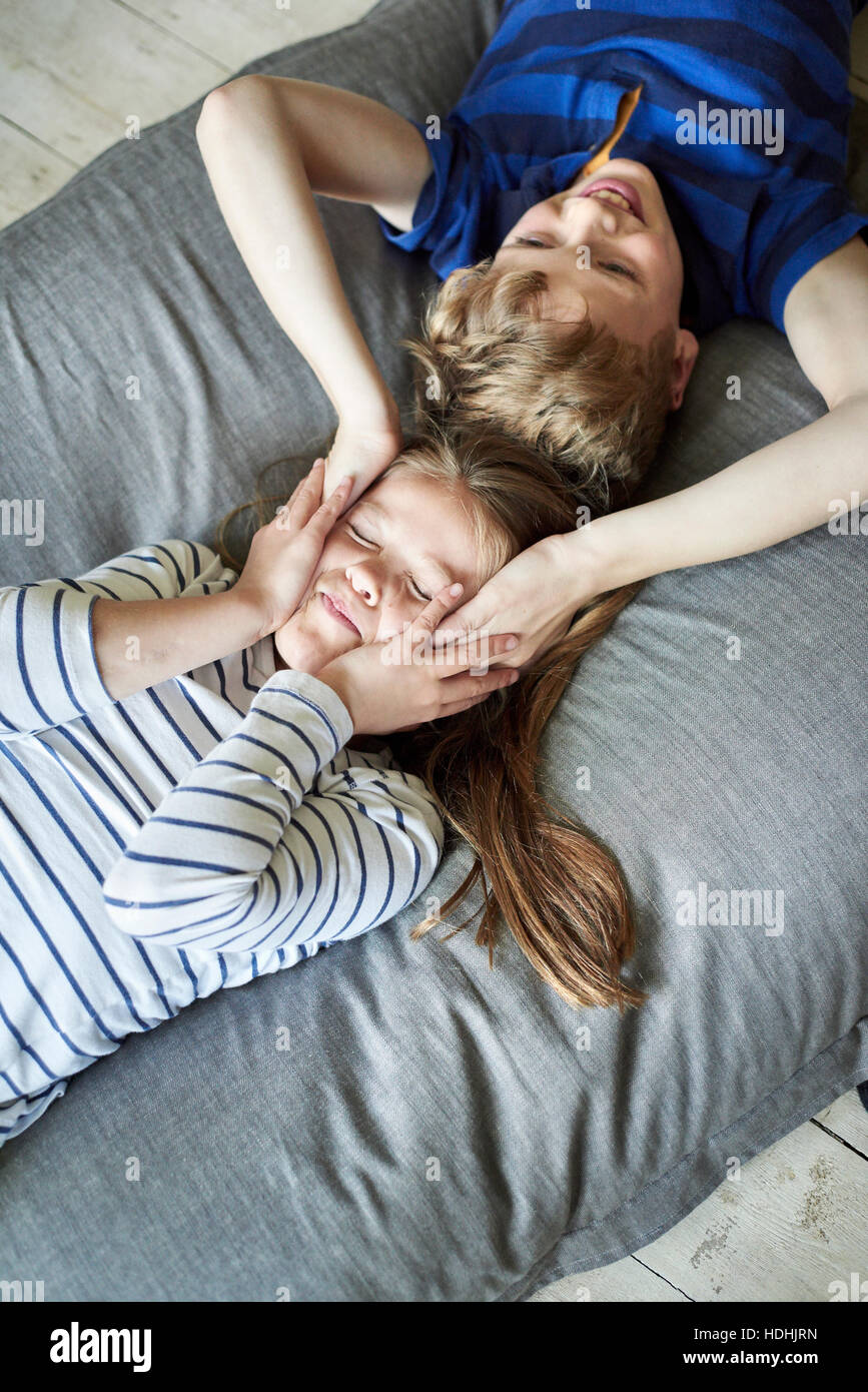 La casa di famiglia. Un ragazzo e una ragazza sdraiato sul divano con le loro teste vicino insieme. Vista da sopra. Foto Stock