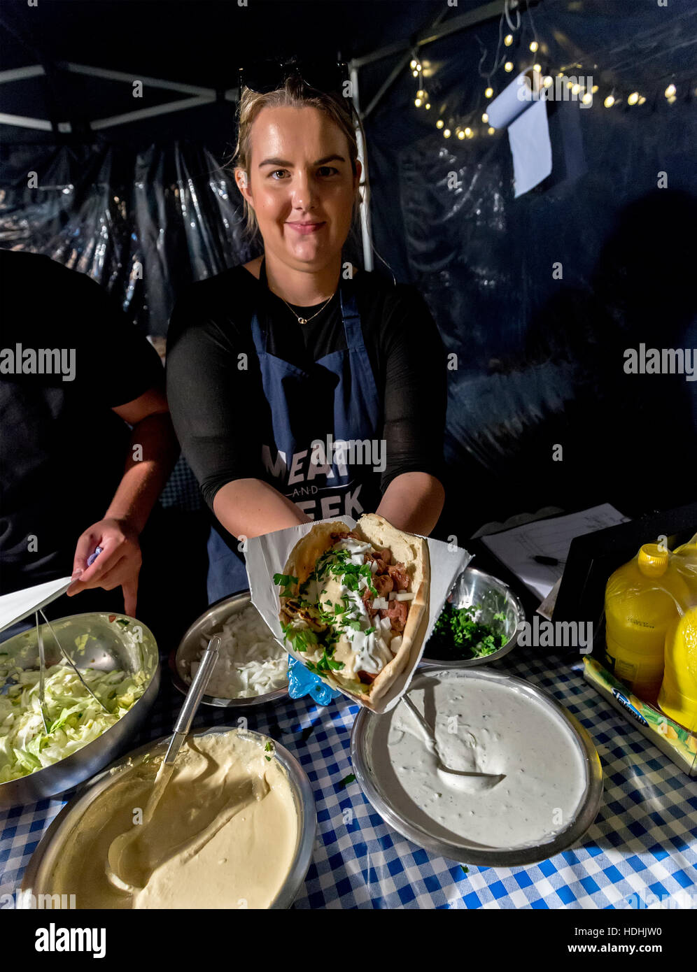 Donna che serve cibo nel pane pitta in stallo a la cucina di strada circo, Cardiff Wales, Regno Unito Foto Stock
