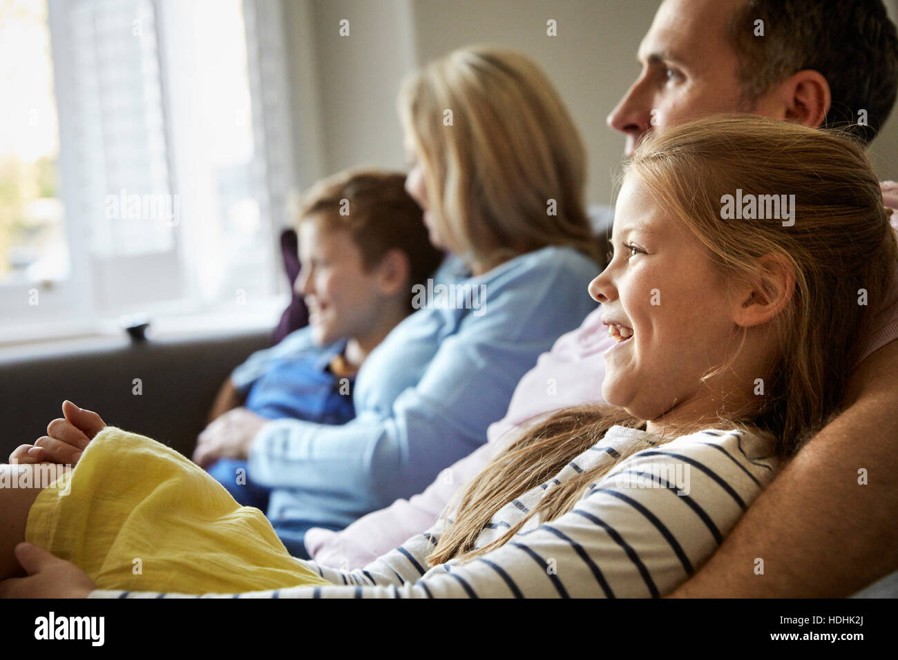 Una famiglia a casa. Due adulti e due bambini seduti su un divano insieme. Foto Stock