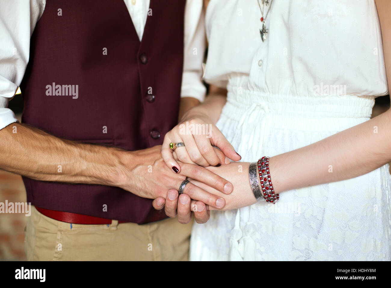 Maschio e femmina tenendo le mani. Mani con boho chic accessori close-up. Coppie in viaggio di nozze. Foto Stock
