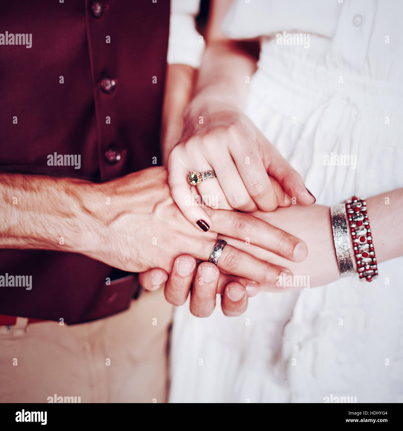 Maschio e femmina tenendo le mani. Mani con boho chic accessori close-up. Coppie in viaggio di nozze. Foto Stock