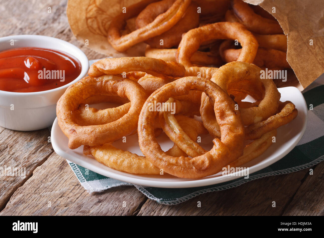 Anelli di cipolla fritti e ketchup vicino sul tavolo orizzontale. Foto Stock