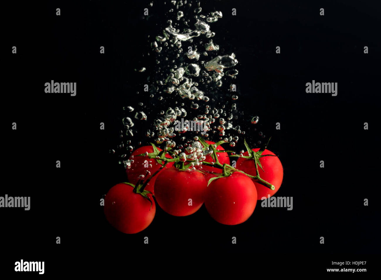 Mini i pomodori in acqua con bolle d'aria. Foto Stock