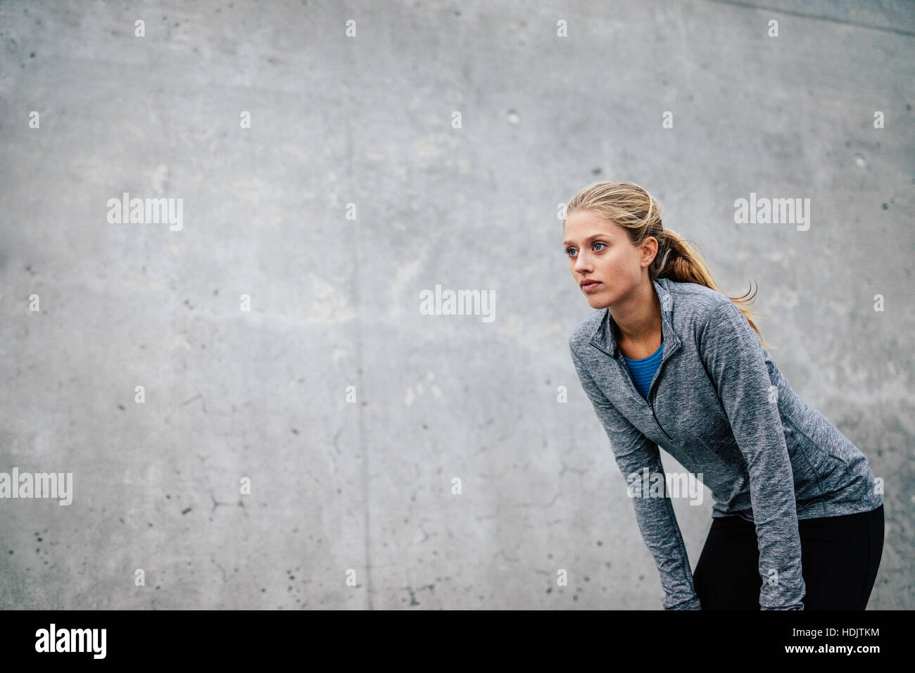 Sport Giovane donna prendendo pausa dopo una corsa. Focalizzato femminile in piedi piegarsi dopo una sessione in esecuzione in città. Foto Stock