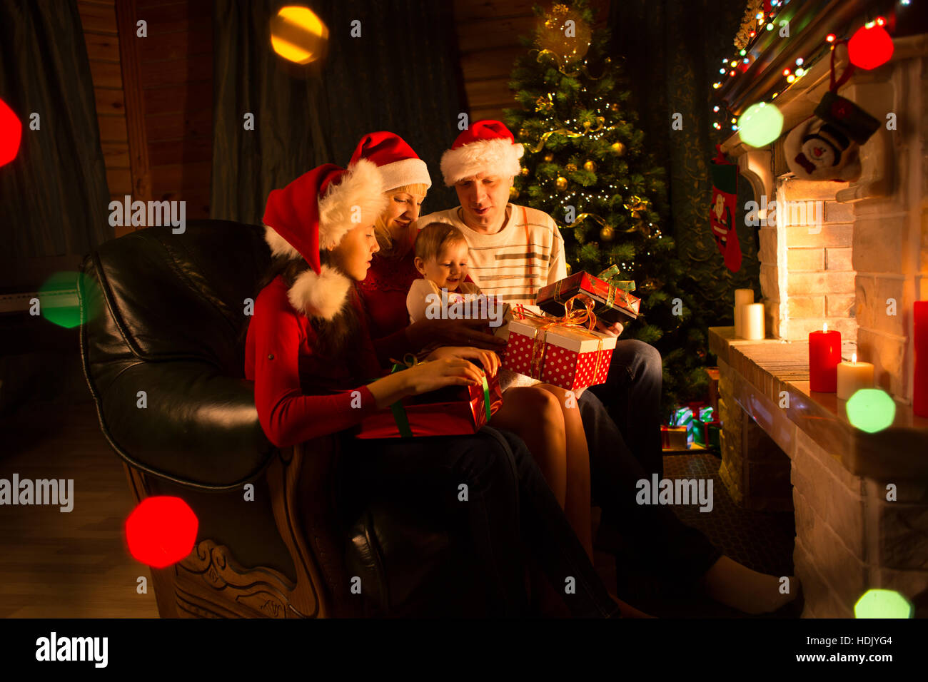 Famiglia lo scambio di doni di fronte al caminetto a albero di Natale Foto Stock
