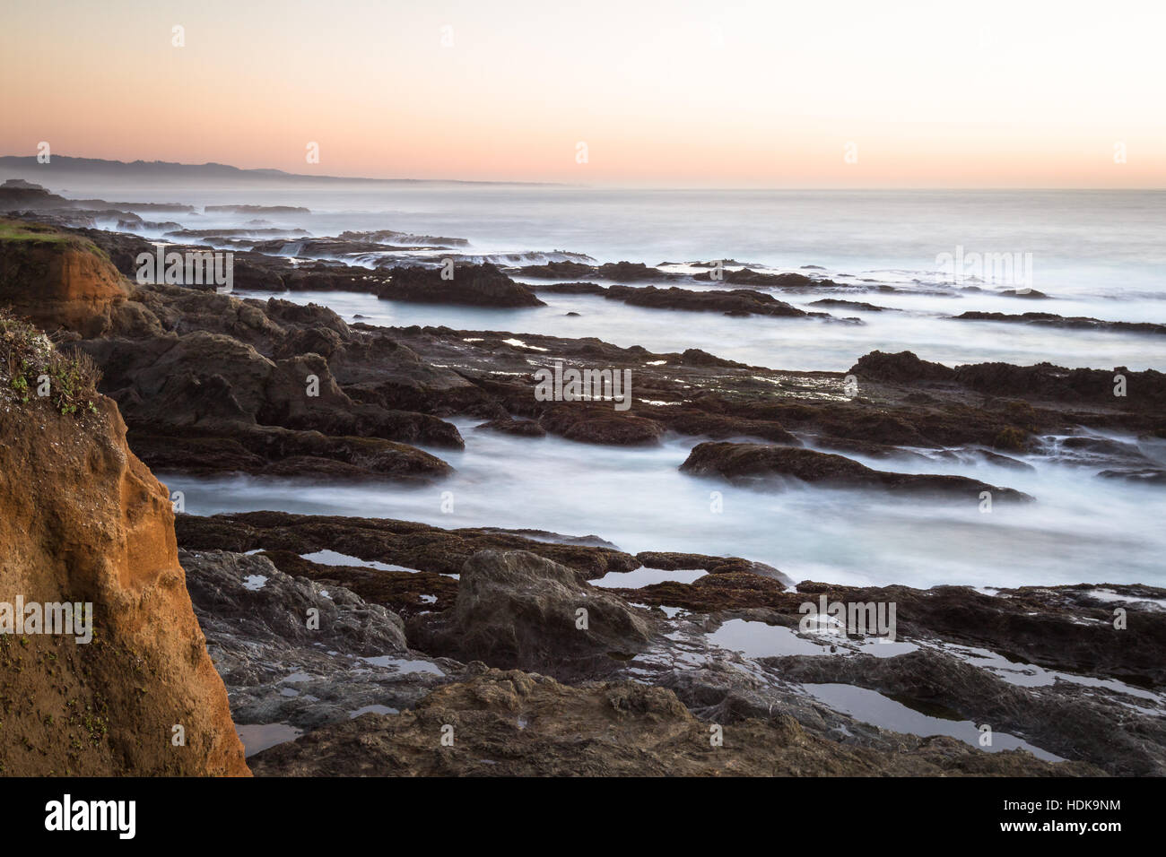 Mare mosso catturate con una lenta velocità di otturatore a creare una rilassante scena con acqua che scorre sulla roccia lavica con un buon effetto di movimento Foto Stock