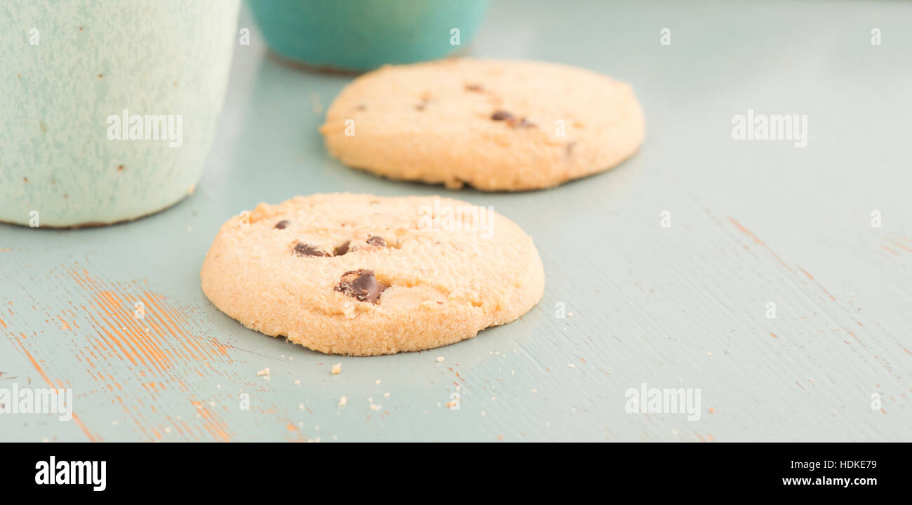 I biscotti al cioccolato e caffè o tè tazze. Sweet Food, dessert o uno spuntino. I cookies sono servite su un tavolo da cucina. Foto Stock