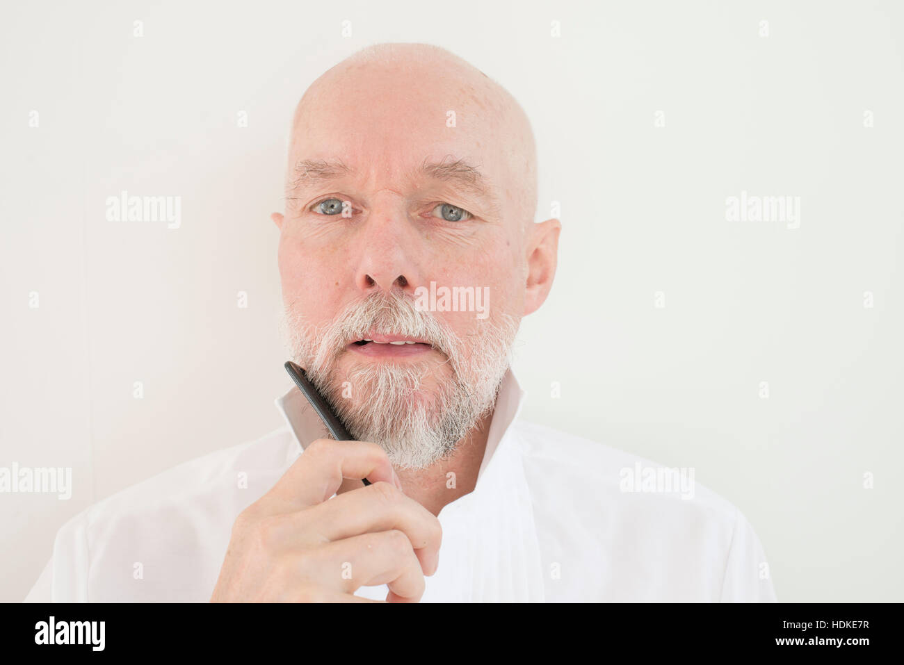 Il vecchio uomo pettinatura di barba e baffi con pettine. Gravi adulti senior di prendersi cura dei suoi capelli facciali. Foto Stock