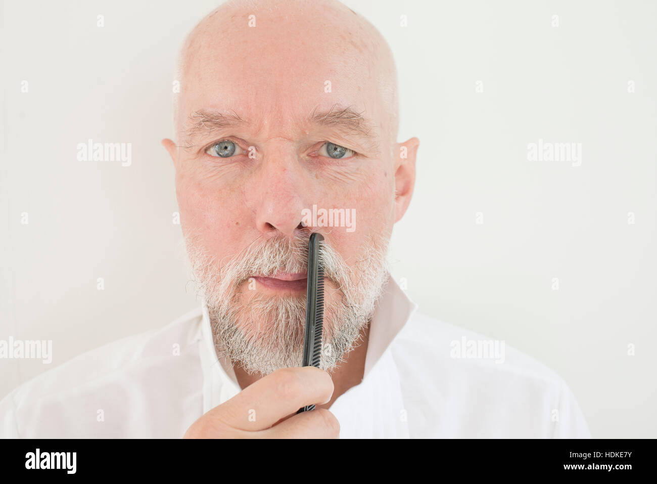 Il vecchio uomo pettinatura di barba e baffi con pettine. Gravi adulti senior di prendersi cura dei suoi capelli facciali. Foto Stock