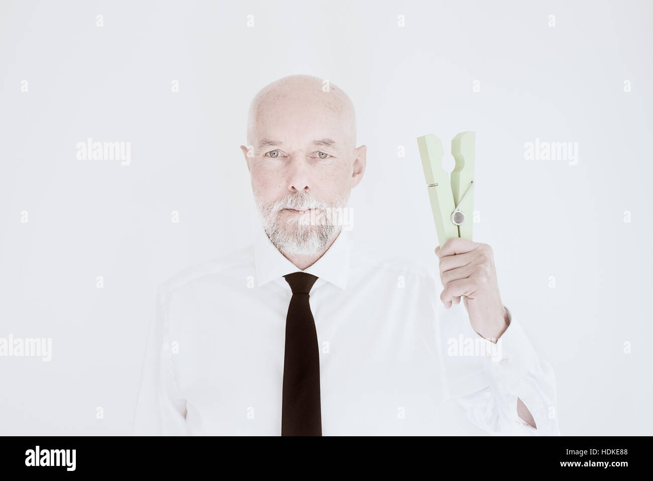 Il Vecchio Uomo in camicia e cravatta azienda big clothespin. Concetto di lavoro domestico per pensionati uomini o business e documenti come un imprenditore senior. Foto Stock