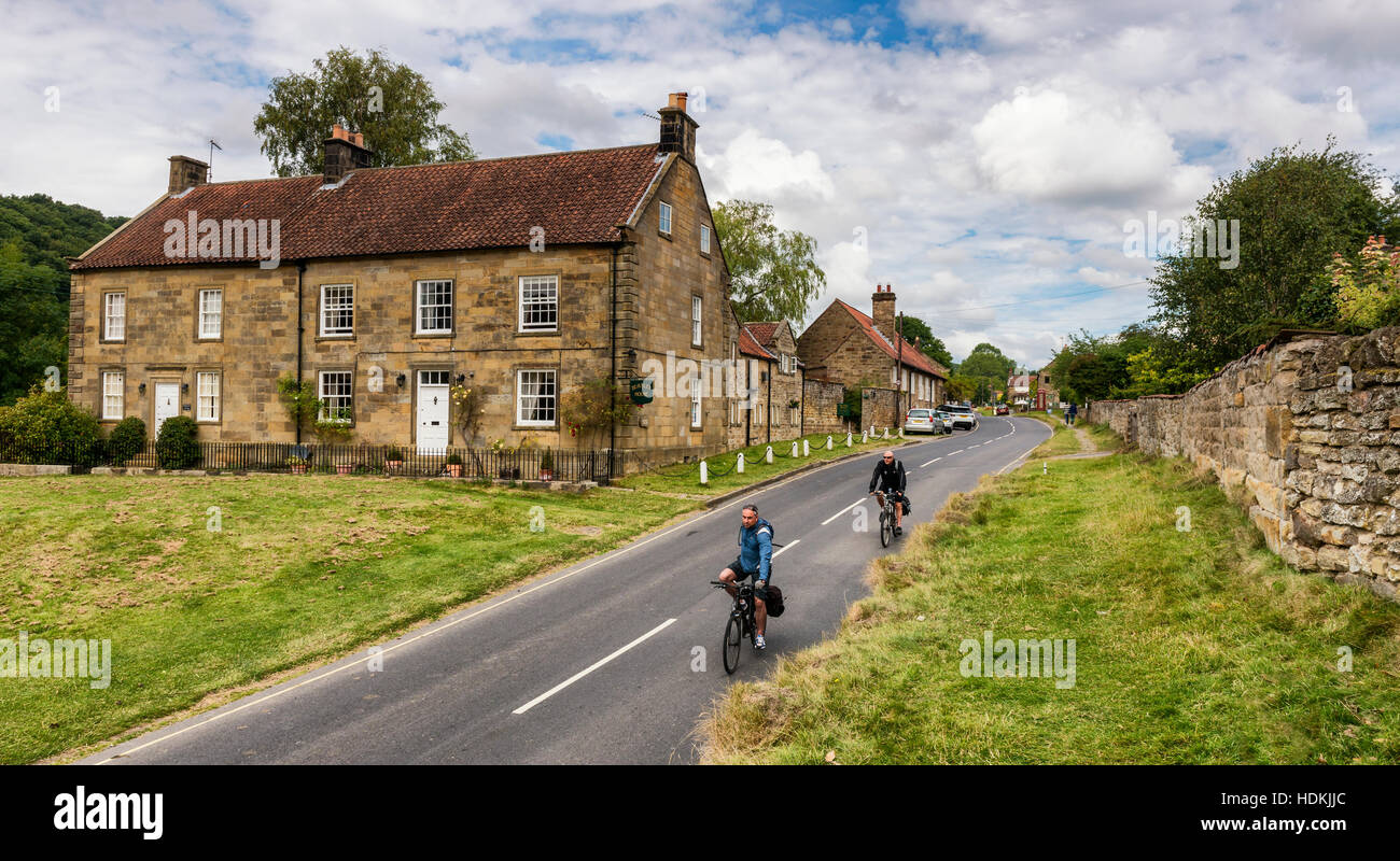 Bike Rider passando attraverso Hutton Le Hole Village Foto Stock