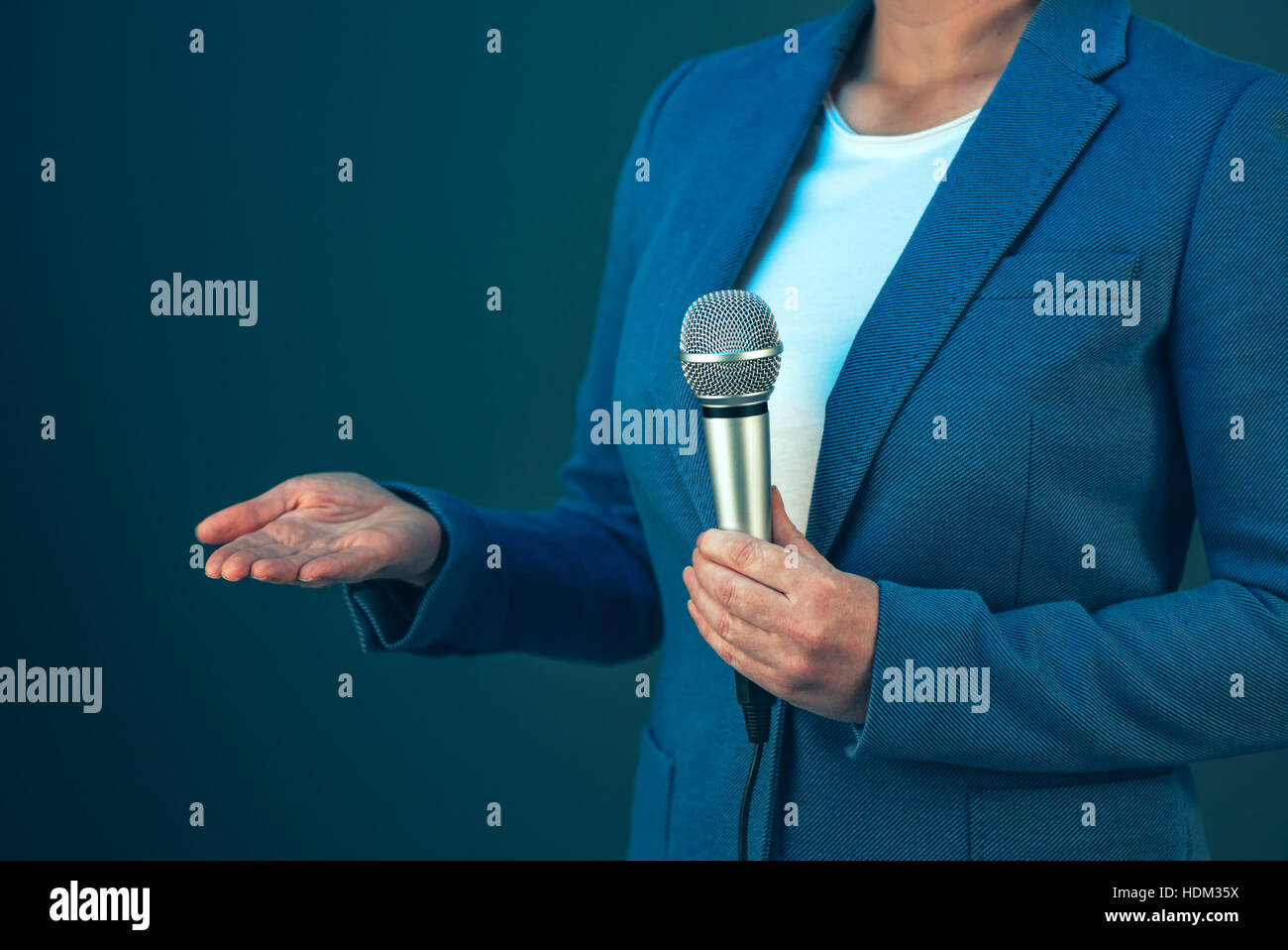 Femmina elegante giornalista televisivo doing business reportage, tenendo il microfono in mani, ultime notizie concept Foto Stock