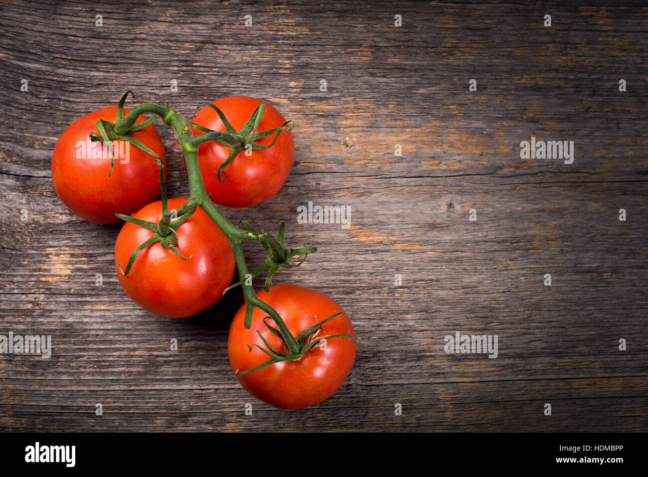 Grappolo di pomodori sul tavolo di legno nella luce naturale Foto Stock