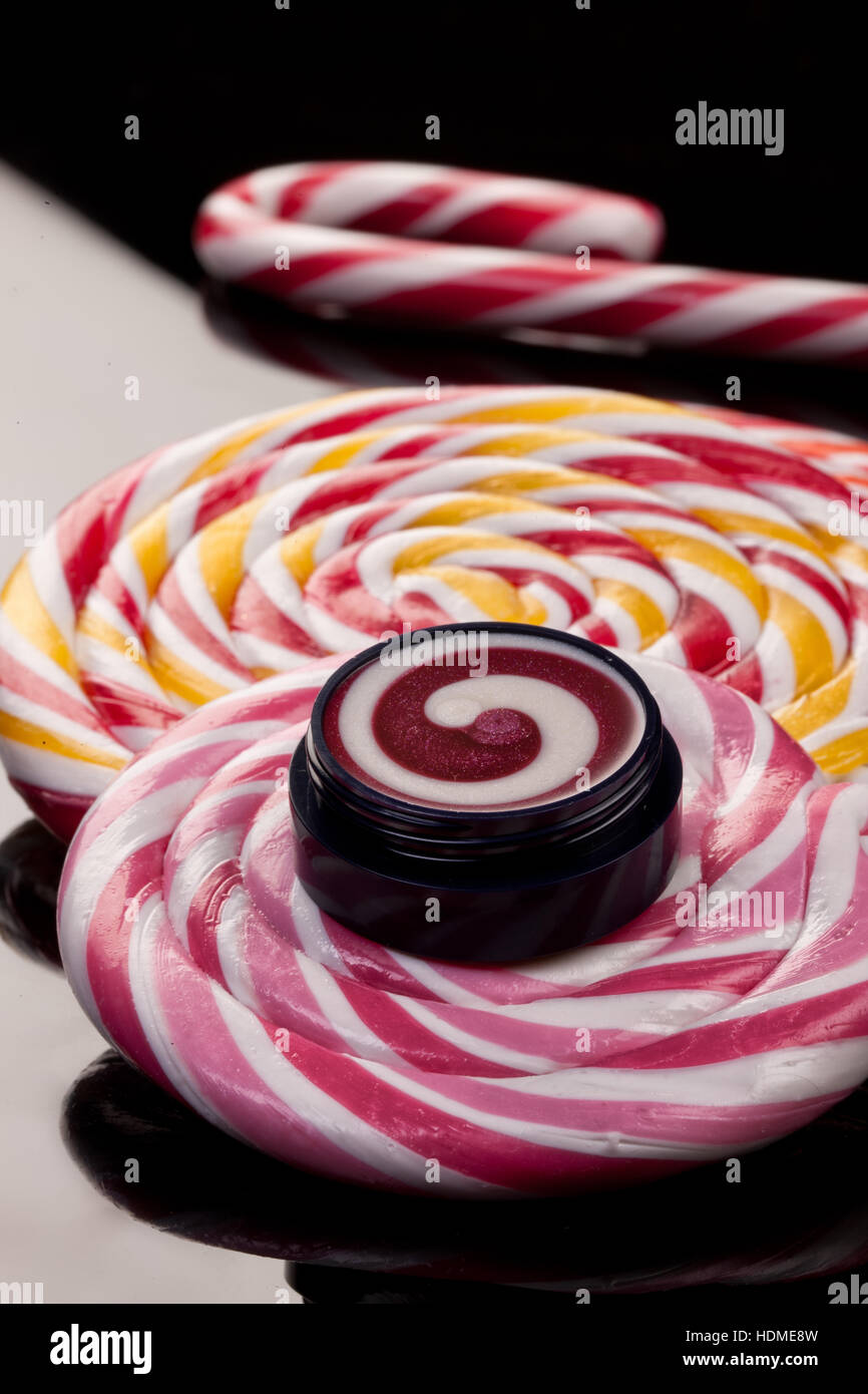 Crema cosmetica e lollipop su un vetro di sfondo per studio Foto Stock