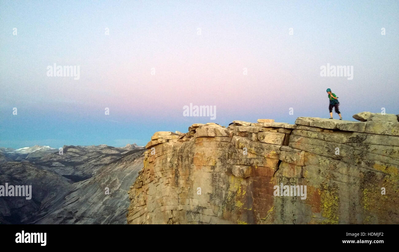 Scalatore femmina guardando giù mezza cupola al tramonto, il Parco Nazionale di Yosemite Foto Stock