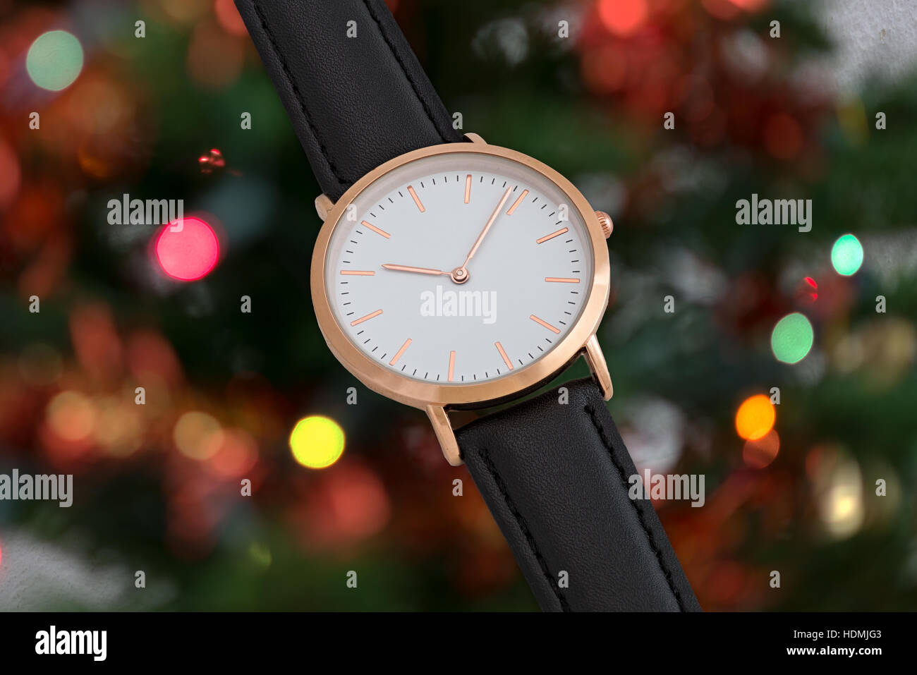 Cinturino in cuoio nero orologio da polso in tempo di Natale nella parte anteriore del albero di Natale sfondo luci Foto Stock