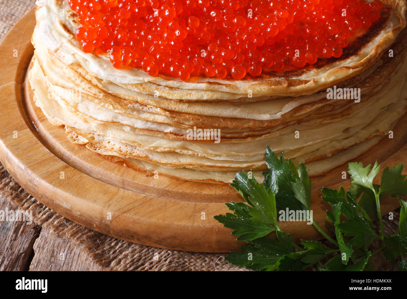 Una pila di sottili crepes con caviale rosso di close-up. orizzontale, stile rustico Foto Stock
