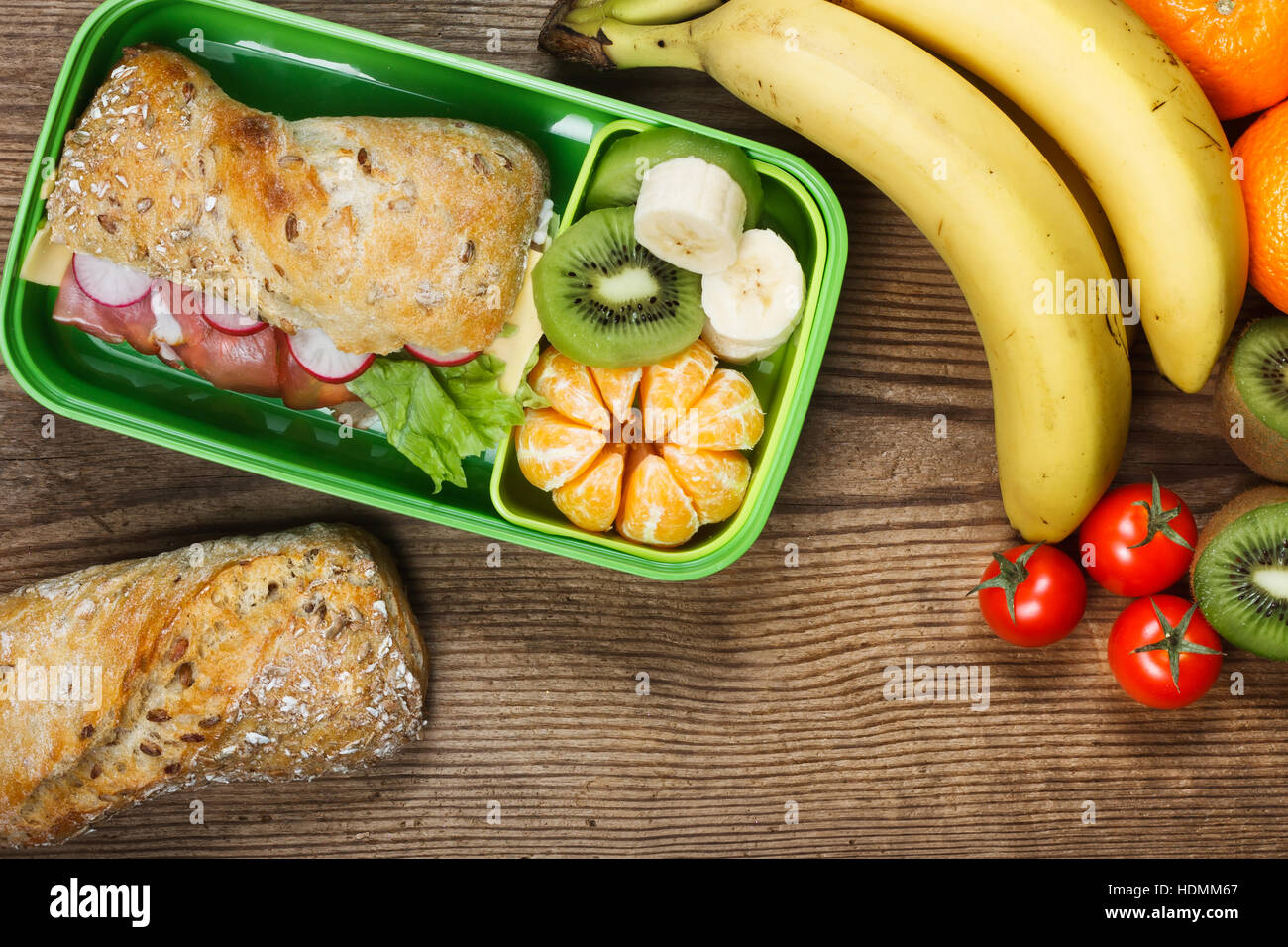 Lunchbox sul tavolo di legno. Panino di prosciutto e frutta in scatola di plastica Foto Stock