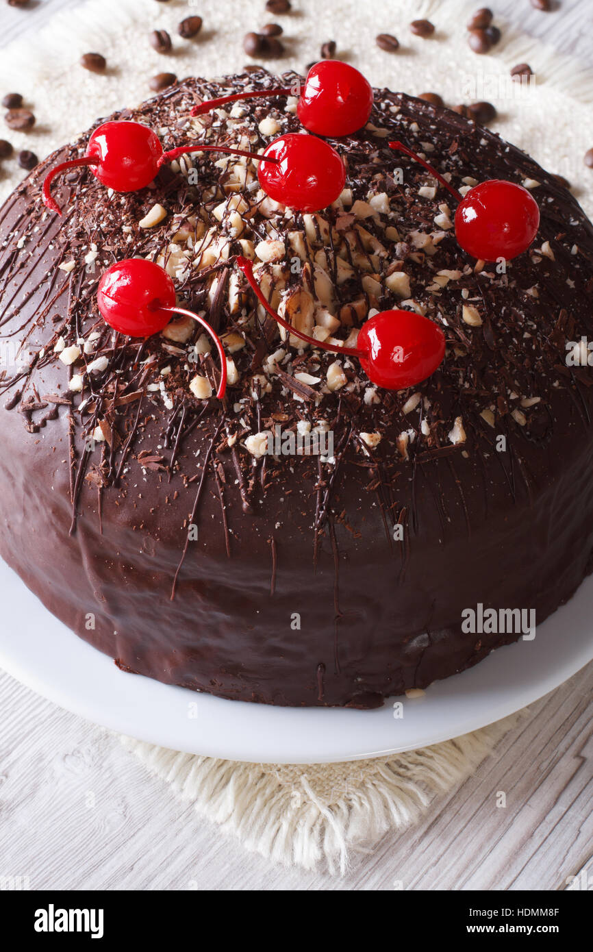 Una deliziosa torta al cioccolato con ciliegie e i dadi sul tavolo. Verticale di close-up Foto Stock