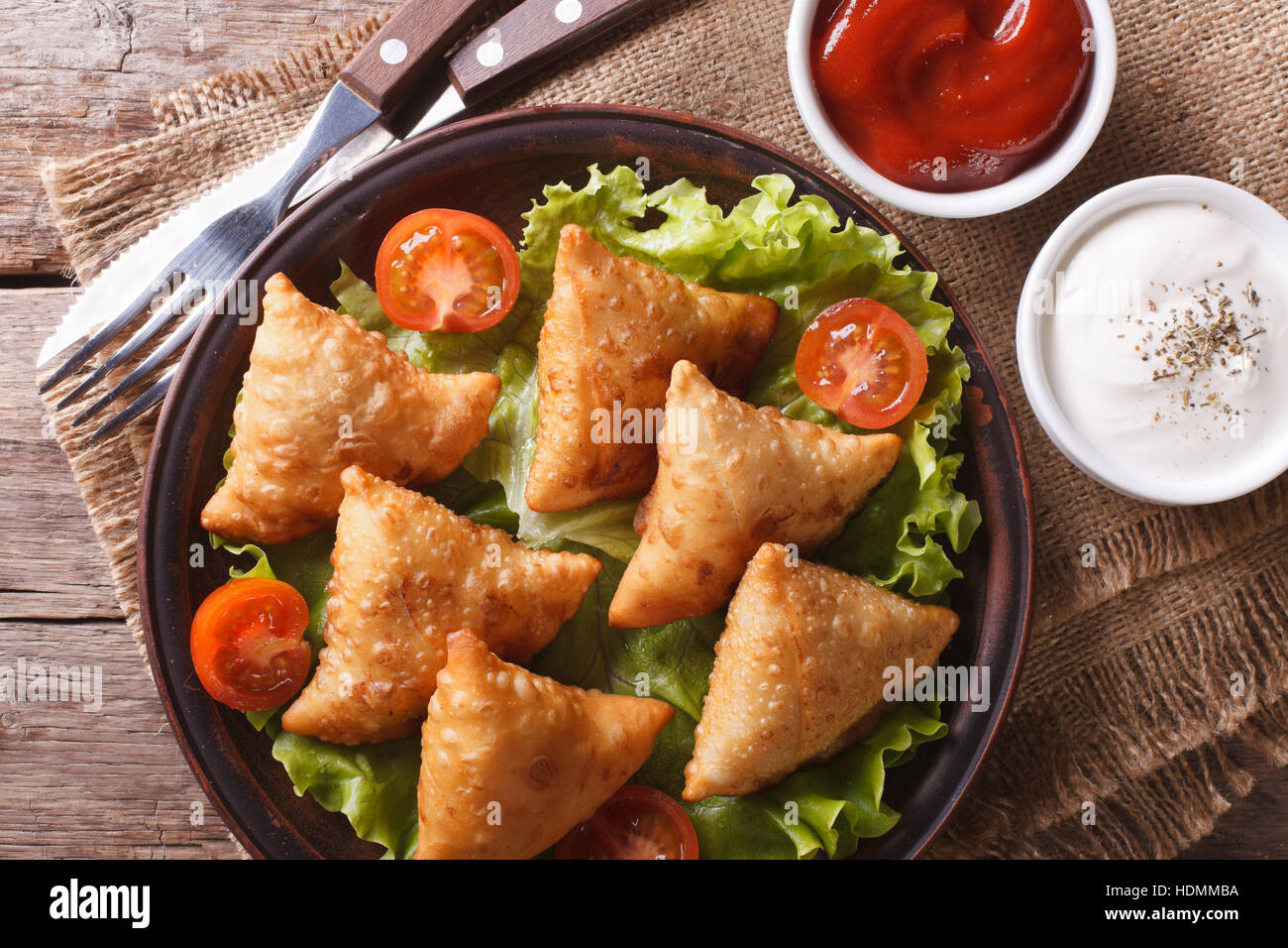 Samosa su una piastra con salsa di pomodori e closeup. vista orizzontale dal di sopra, stile rustico Foto Stock