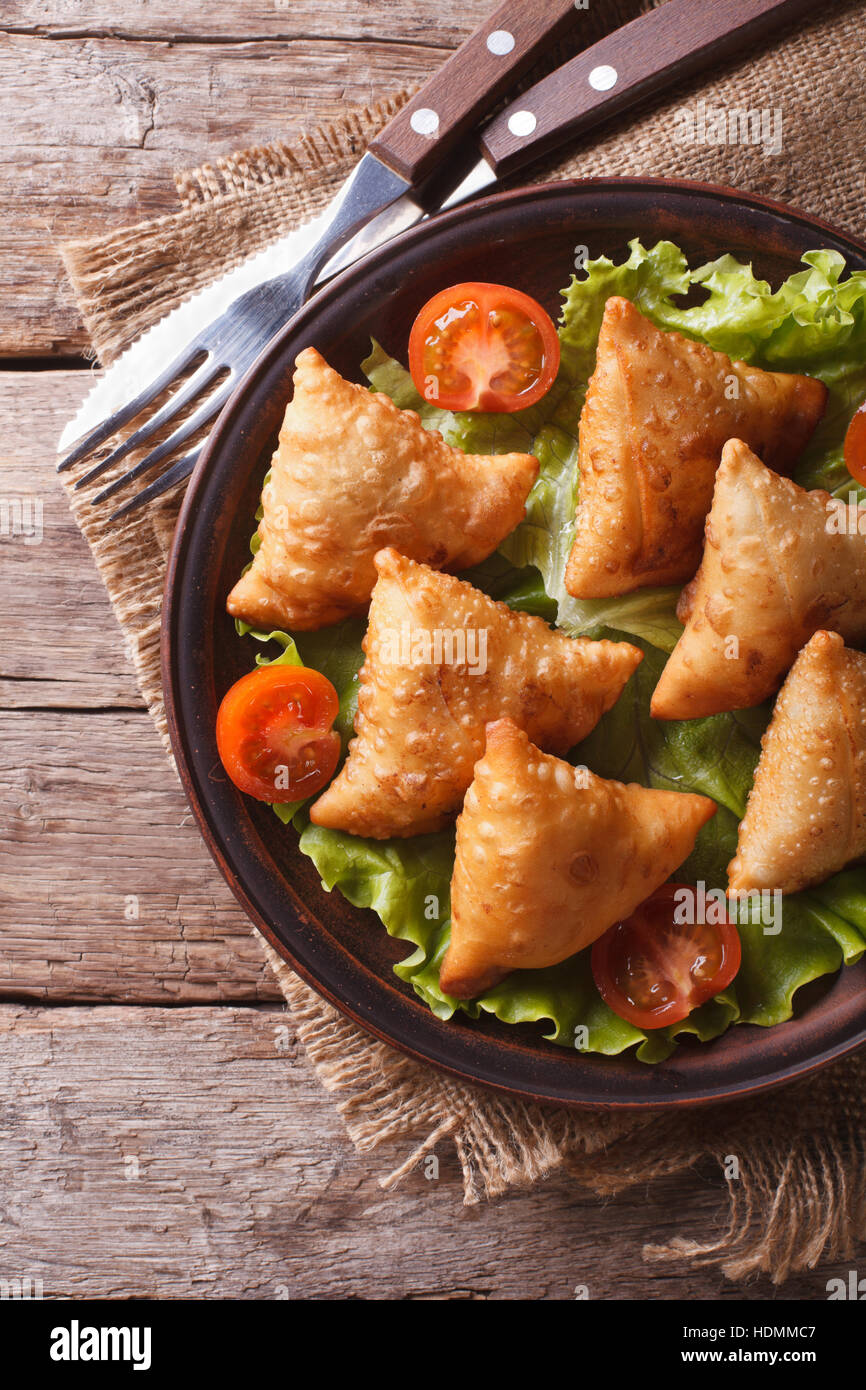 Una deliziosa pasticceria samosa su una piastra di close-up. vista verticale al di sopra, stile rustico Foto Stock