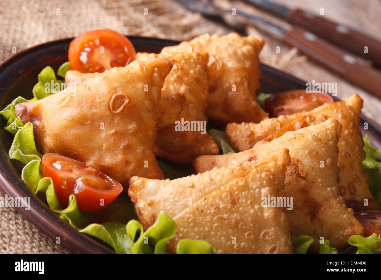 Samosa su una piastra con pomodori e lattuga su un tavolo di legno. orizzontale di close-up Foto Stock