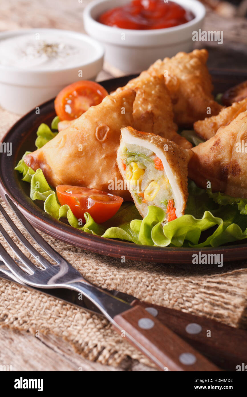 Samosa ripieno di verdure su una piastra di close-up verticale. Foto Stock