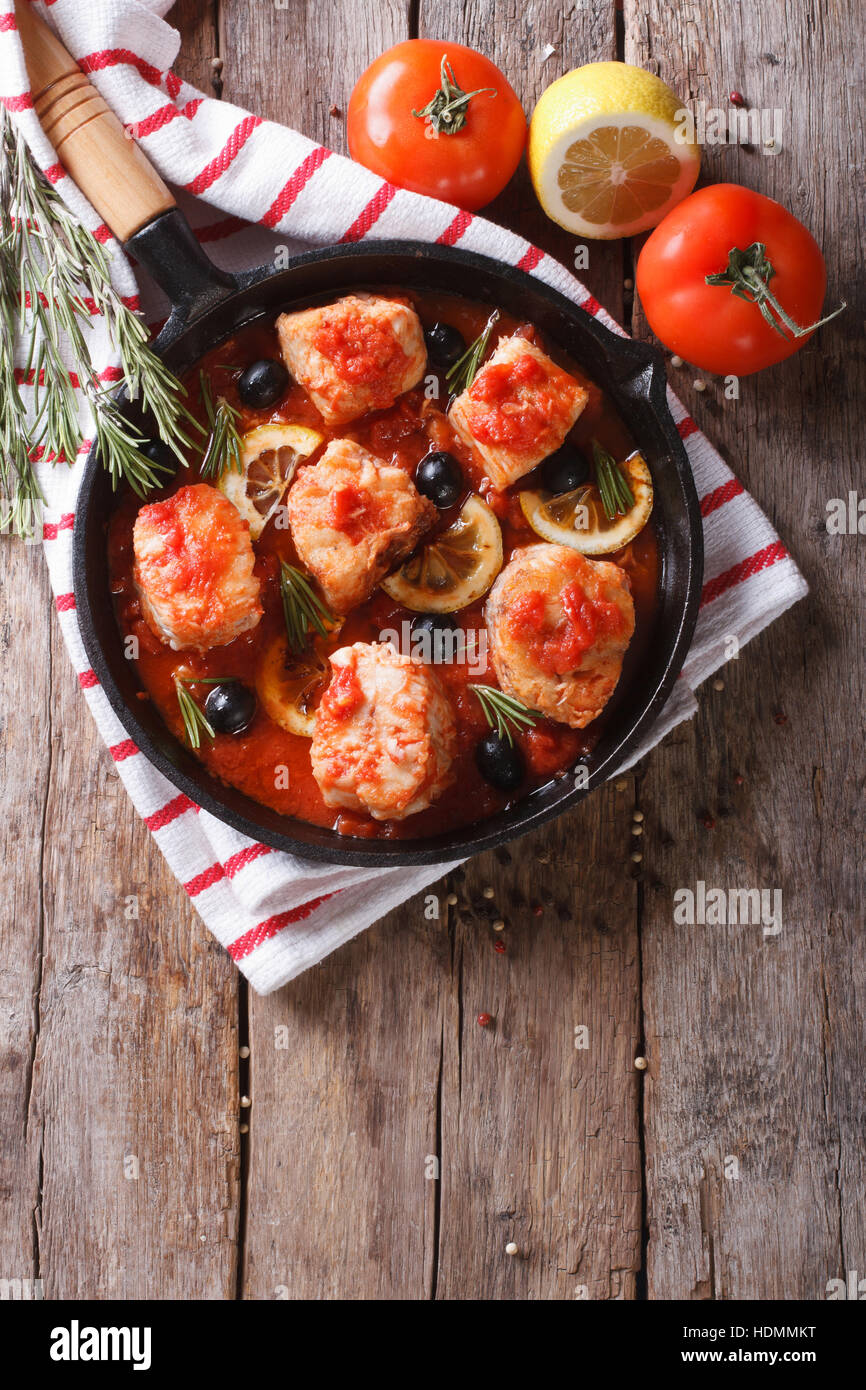 Pezzi di pesce in salsa di pomodoro con olive e limone in una padella.  verticale vista superiore Foto stock - Alamy