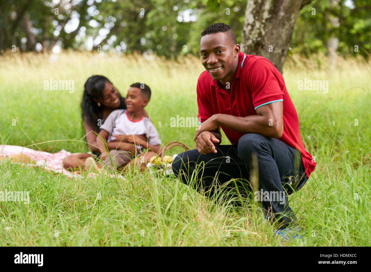 Felice gente nera nel parco della città. Famiglia americana africana con il giovane padre, madre e figlio durante un picnic. Tempo libero per il marito, moglie e bambino. Foto Stock