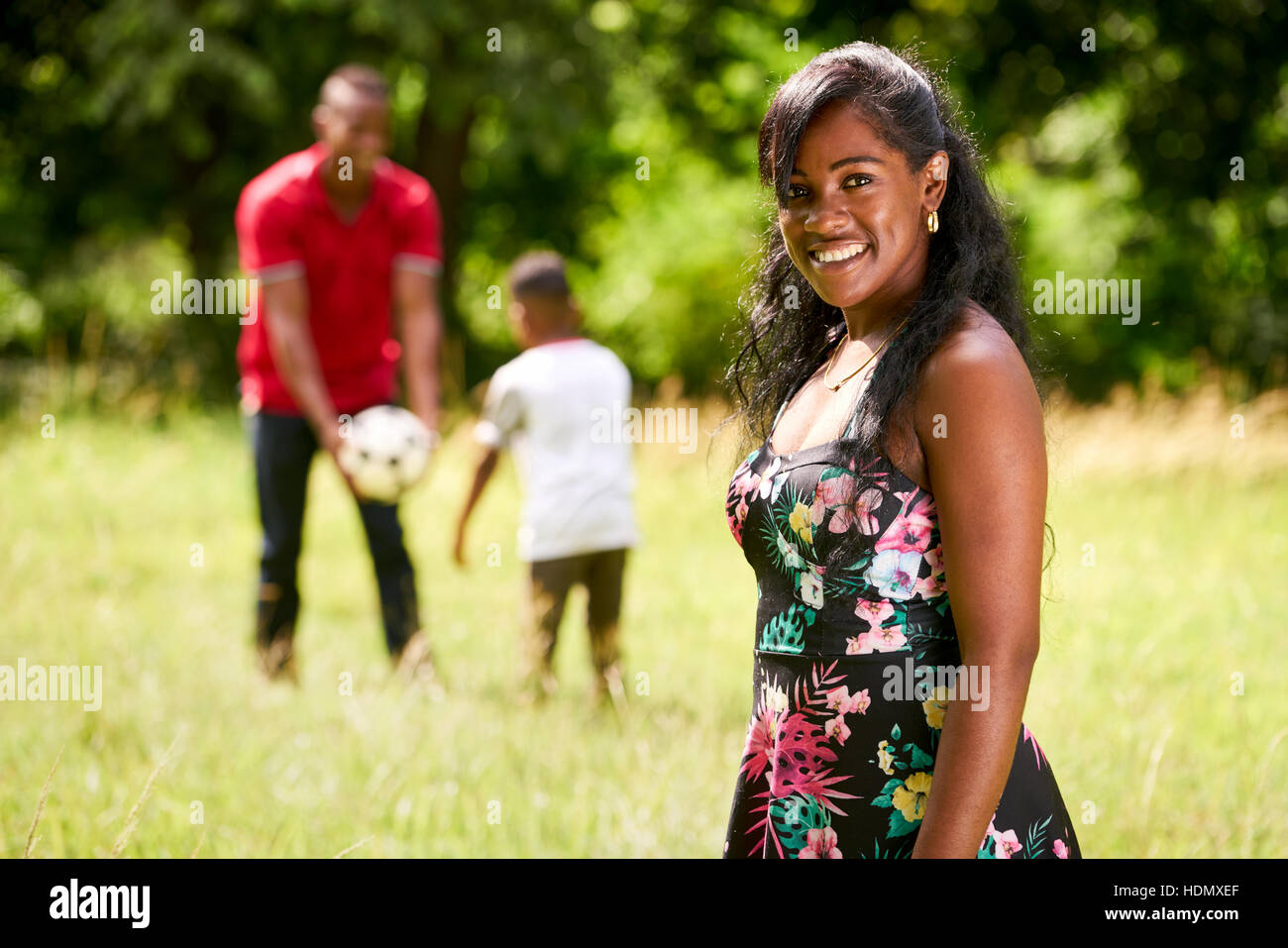 Felice gente nera nel parco. Famiglia americana africana con il giovane padre e figlio si divertono con il calcio. Ritratto di Madre sorridente Foto Stock