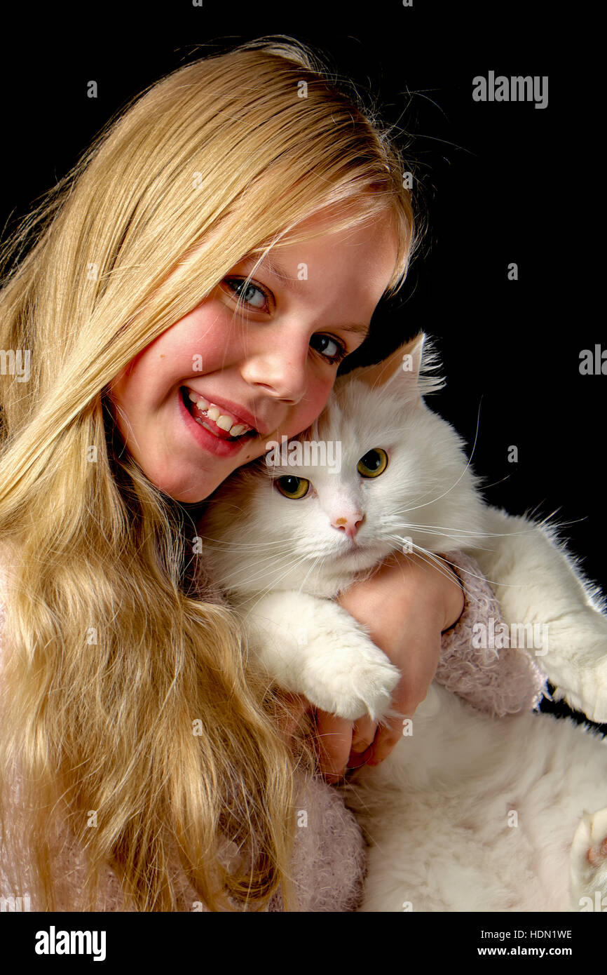 Capelli biondi Ragazza con gatto bianco su sfondo nero Foto Stock