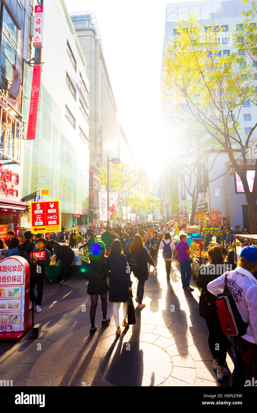 I turisti a piedi giù retroilluminato occupato a Myeongdong strada pedonale dello shopping con commercialismo di negozi, segni e affollato Foto Stock