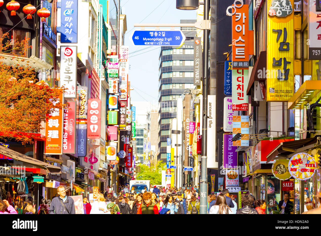 Persone che camminano giù a Myeongdong vivace strada pedonale dello shopping circondato da commercialismo di negozi, segni e affollato Foto Stock