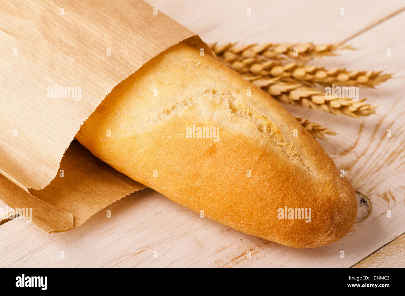 Baguette di pane con spighe di grano su un sfondo di legno Foto Stock