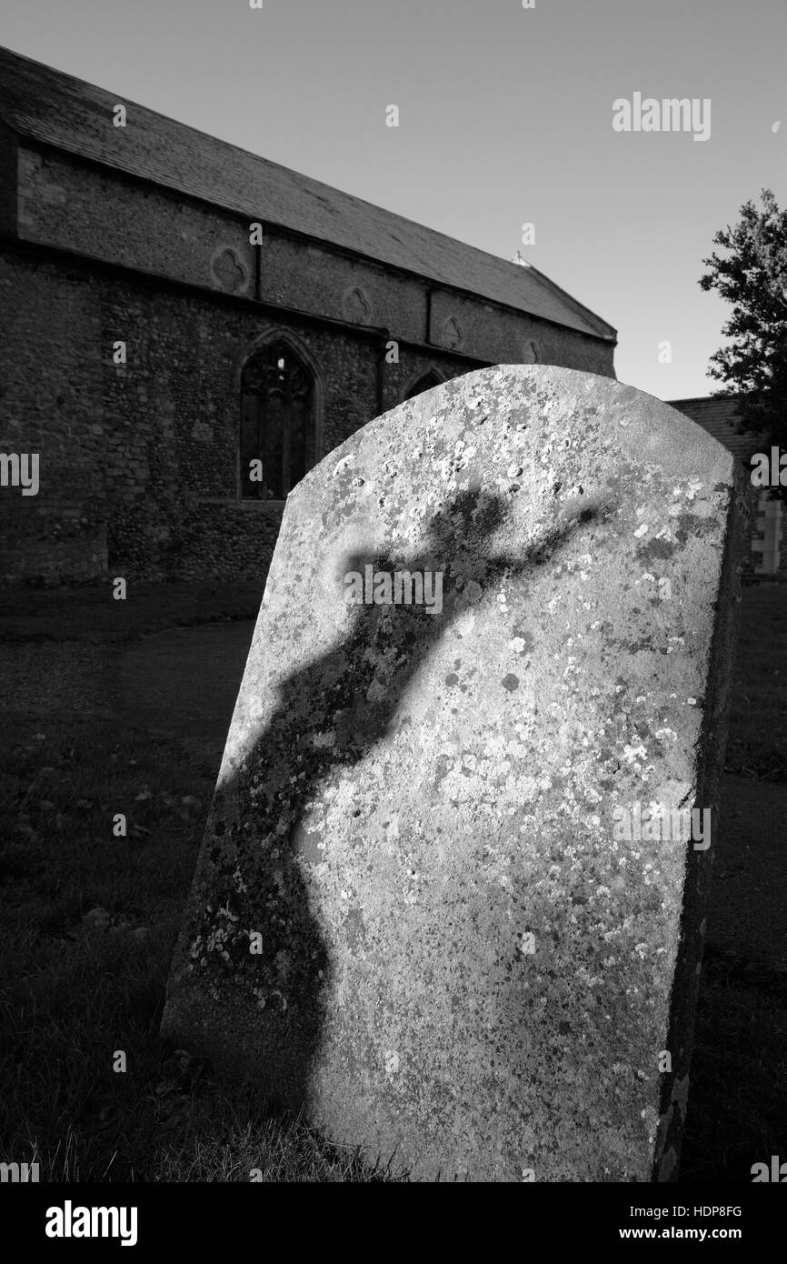 Un ombra su di una lapide dalla statua di un angelico figura in un cimitero. Foto Stock