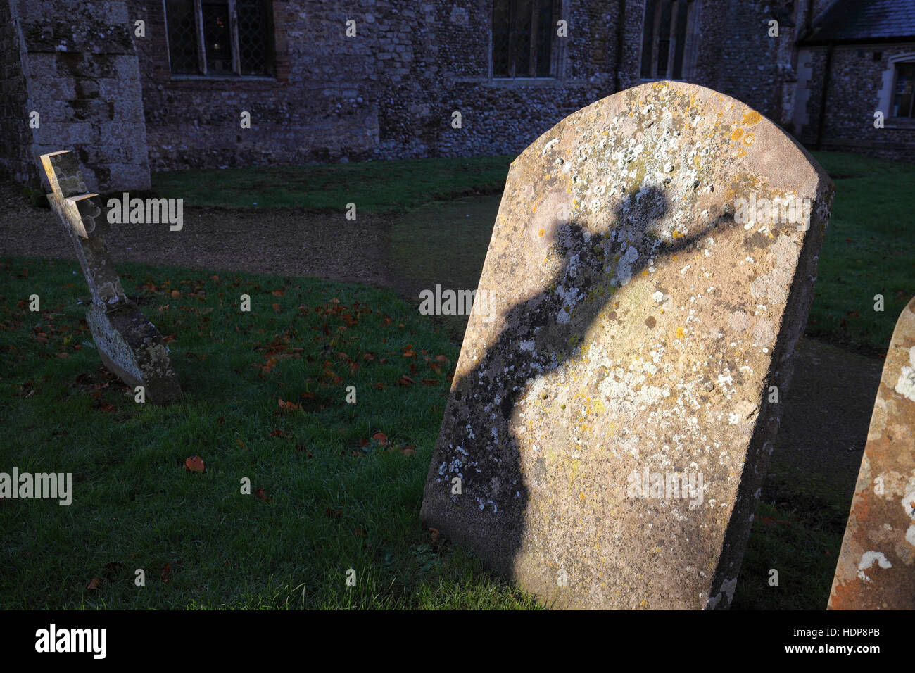 Un ombra su di una lapide dalla statua di un angelico figura in un cimitero. Foto Stock