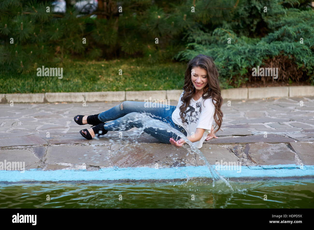 Bella donna seduta vicino alla fontana nel Parco Foto Stock