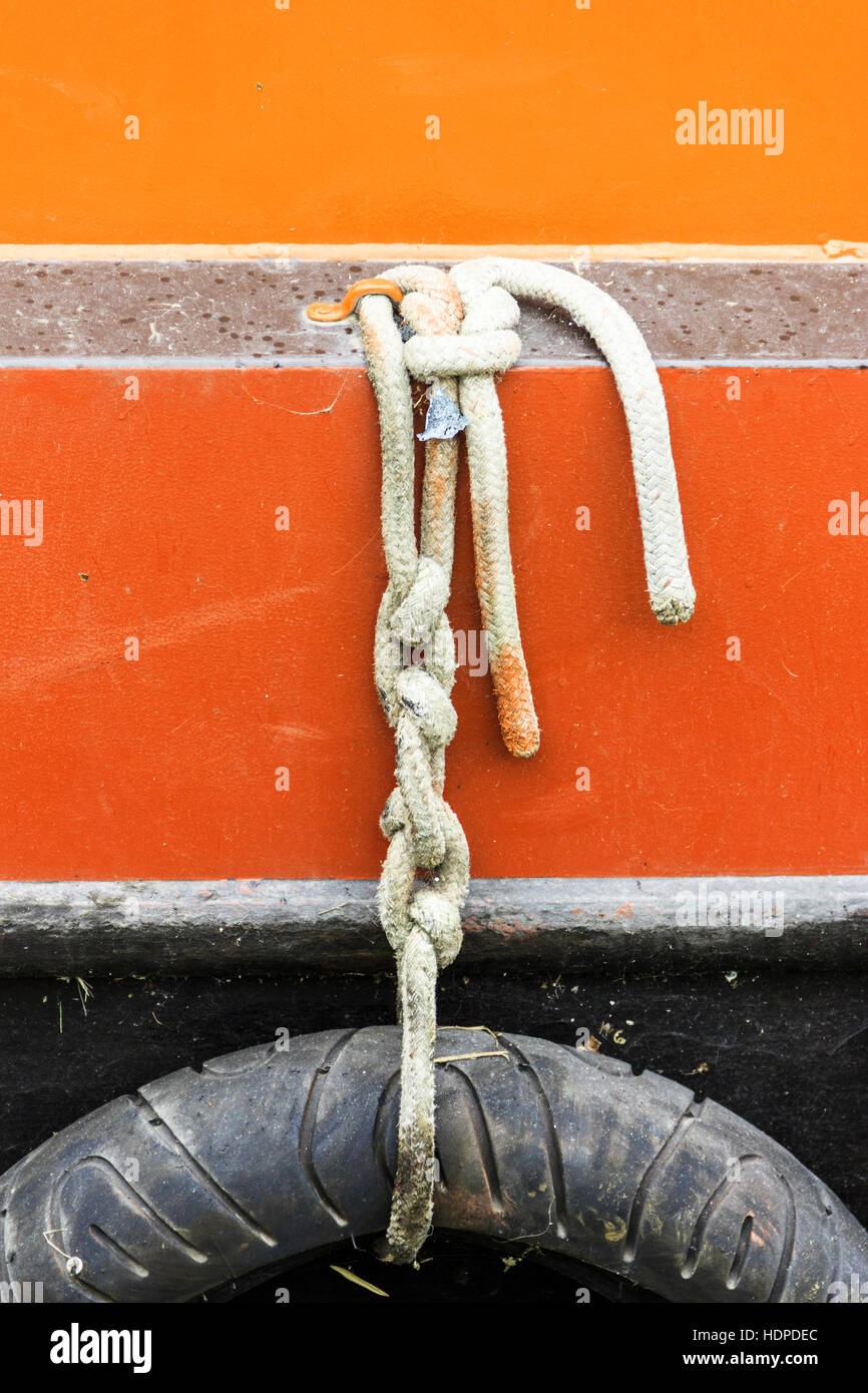 Immagine astratta di un pneumatico autovettura usata come un parafango su un rosso e verniciato giallo narrowboat ormeggiato sul Regent's Canal, King's Cross, London, Regno Unito Foto Stock
