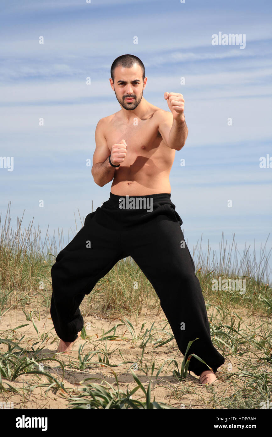 Giovane maschio fighter esercitando su di una collina di sabbia Foto Stock