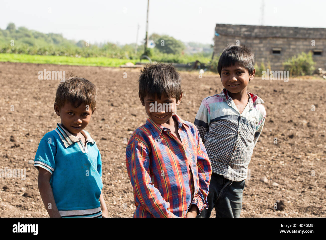 Agriturismo operaio i bambini attendere per i loro genitori per finire per il giorno, la raccolta del cotone in Gujurat, a nord-ovest di India. Foto Stock