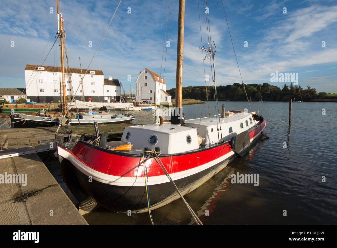 Woodbridge Tide Mill, Fiume Deben, Suffolk, Regno Unito. Novembre. Rosso luminoso convertito chiatta olandese in primo piano. Foto Stock